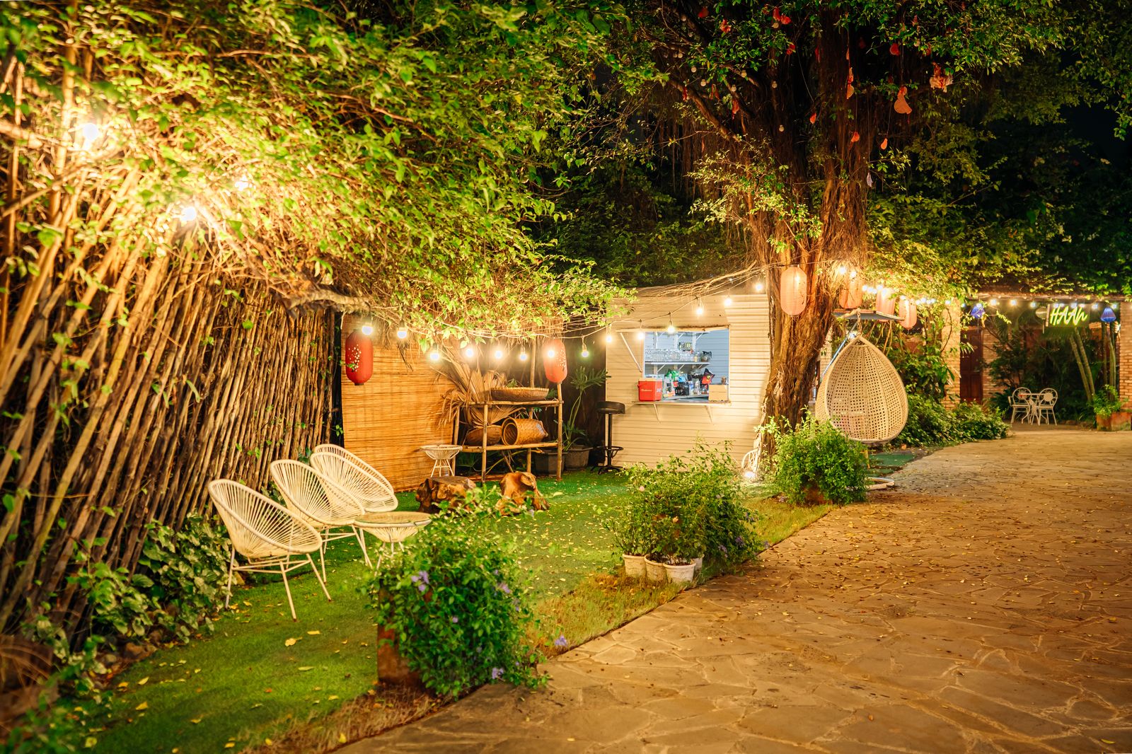 Không gian sân vườn lung linh buổi đêm với đèn trang trí và ghế ngồi thư giãn tại Haan Boutique Resort Thủ Đức.